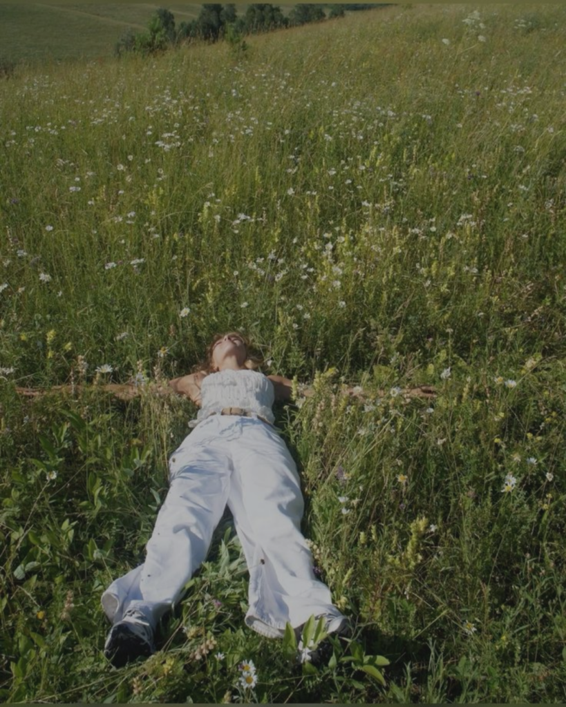 Woman lying in a wildflower meadow, relaxed and at ease