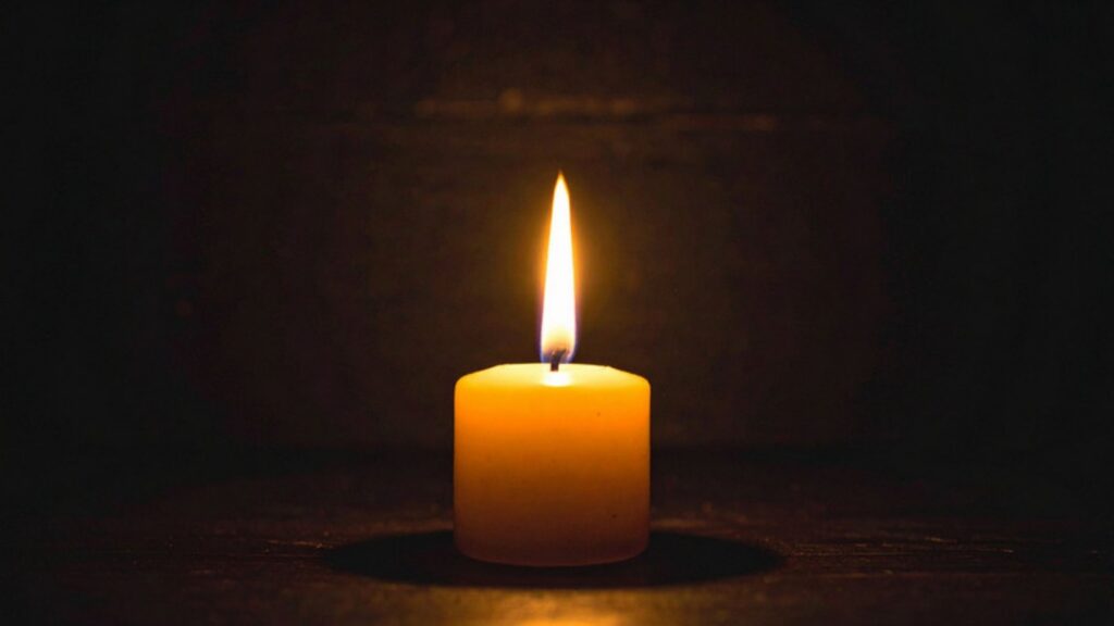 A single lit candle glowing in a dark room