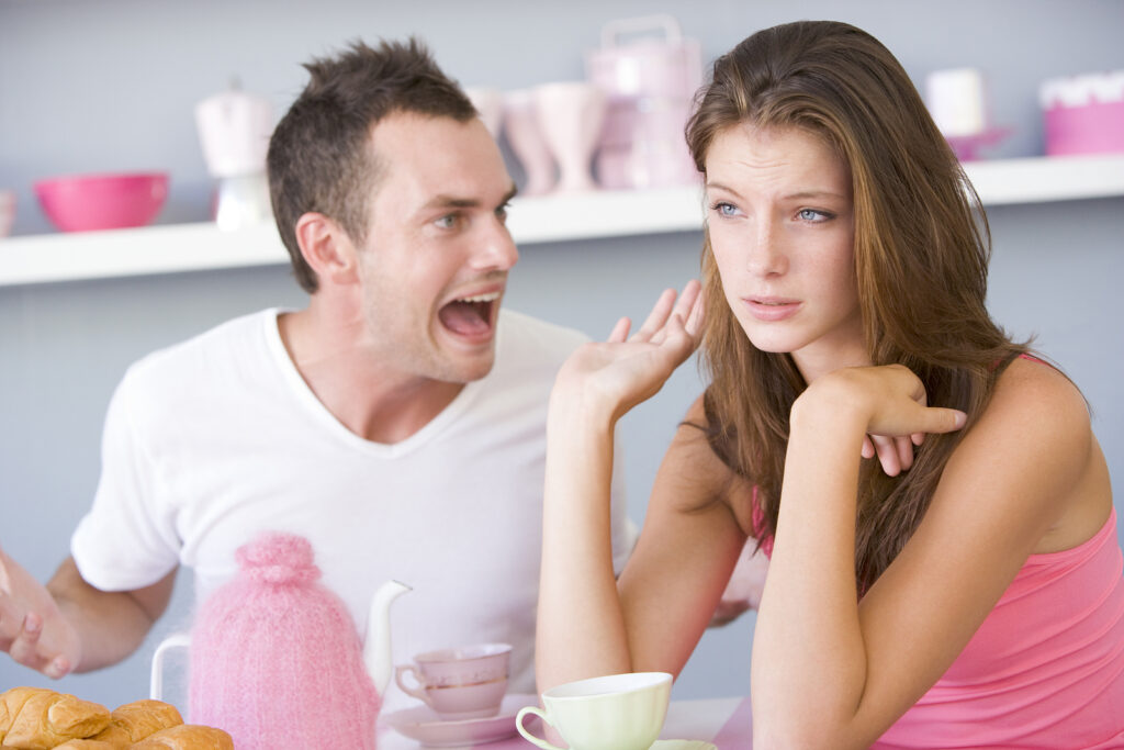 Man arguing while his partner looks away at the breakfast table