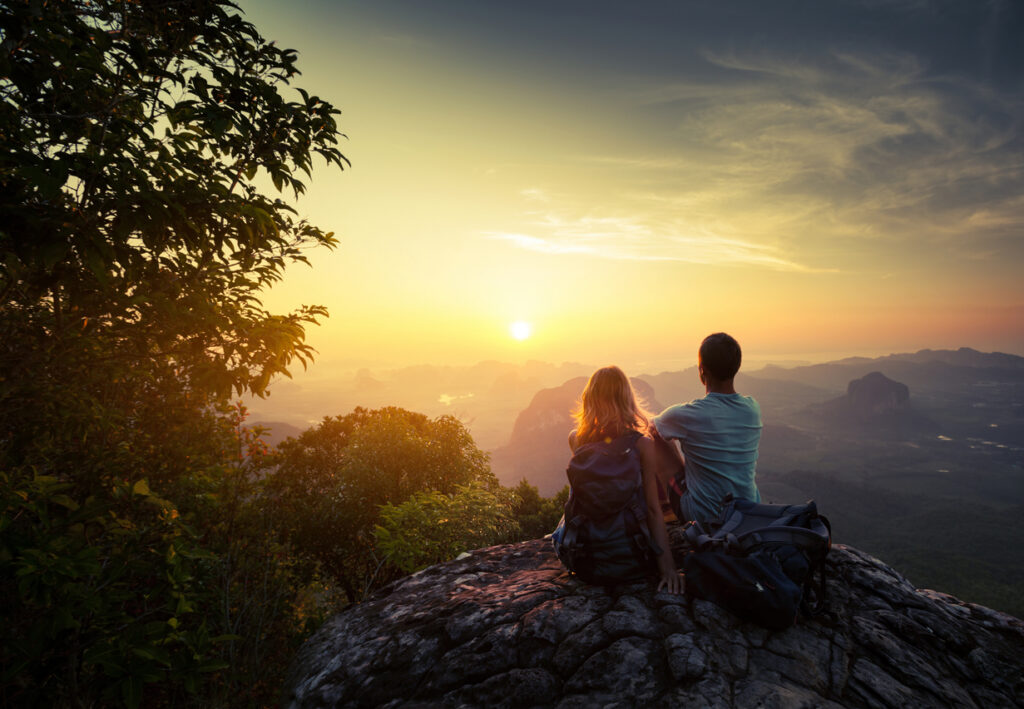 Couple sitting together on a mountaintop at sunrise