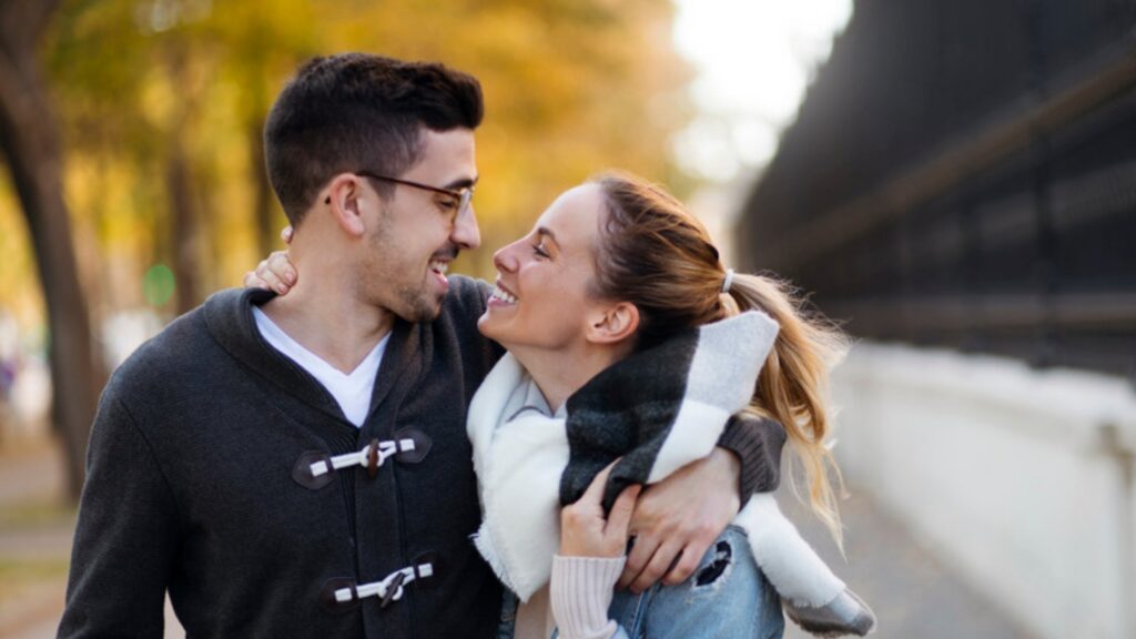 Couple walking arm in arm and laughing on an autumn street