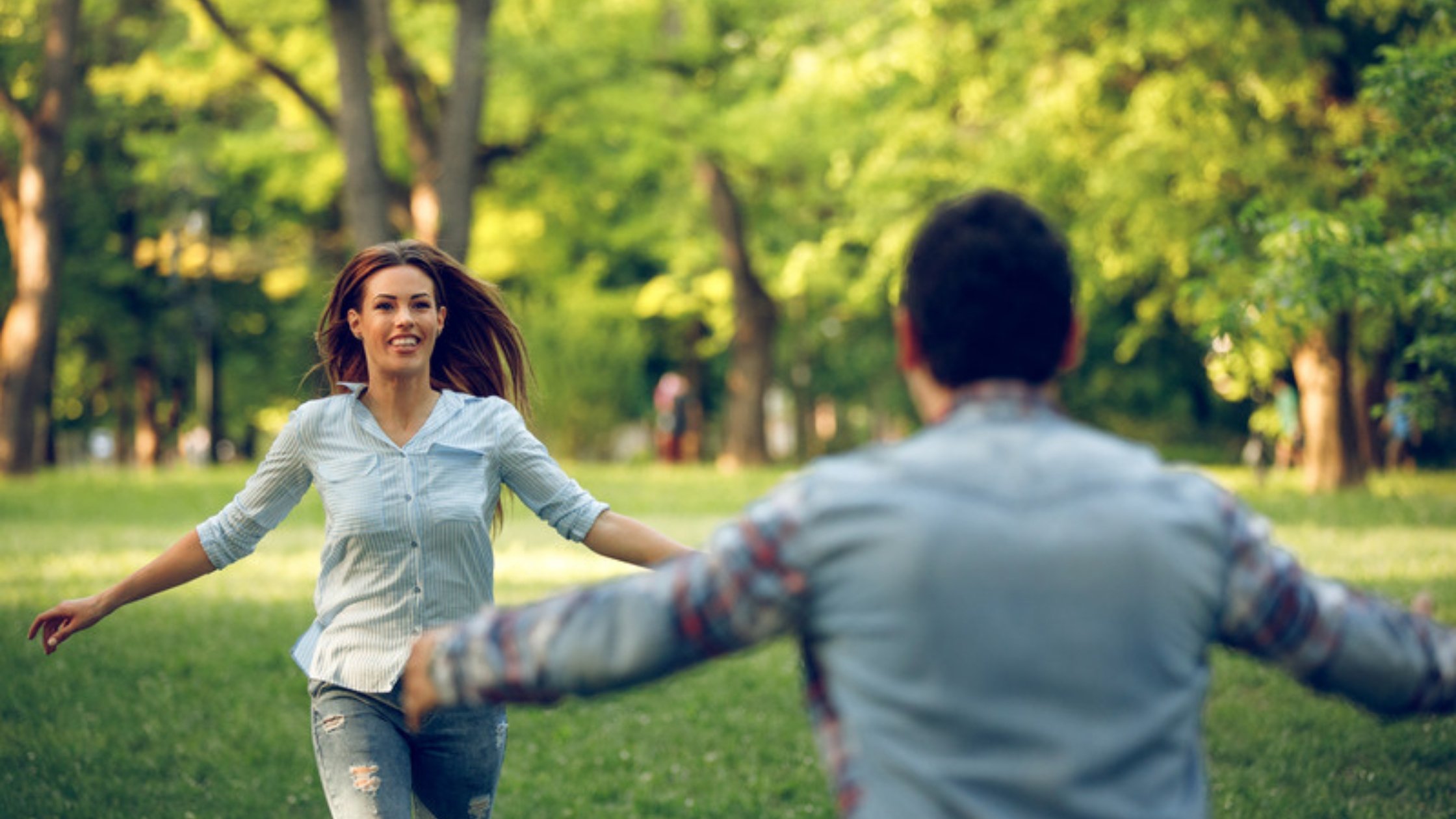 Woman running toward her partner with open arms in a park