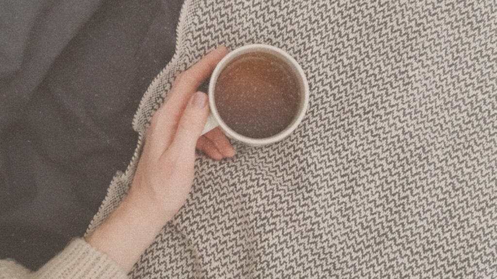 Hand holding tea on a knit blanket