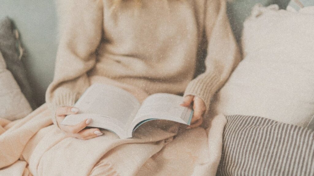 Woman reading in a cream sweater