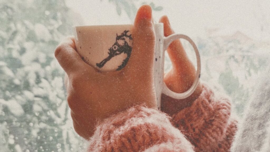 Knit sweater and mug by a snowy window